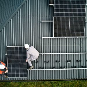 Men workers installing solar panels on roof of house.